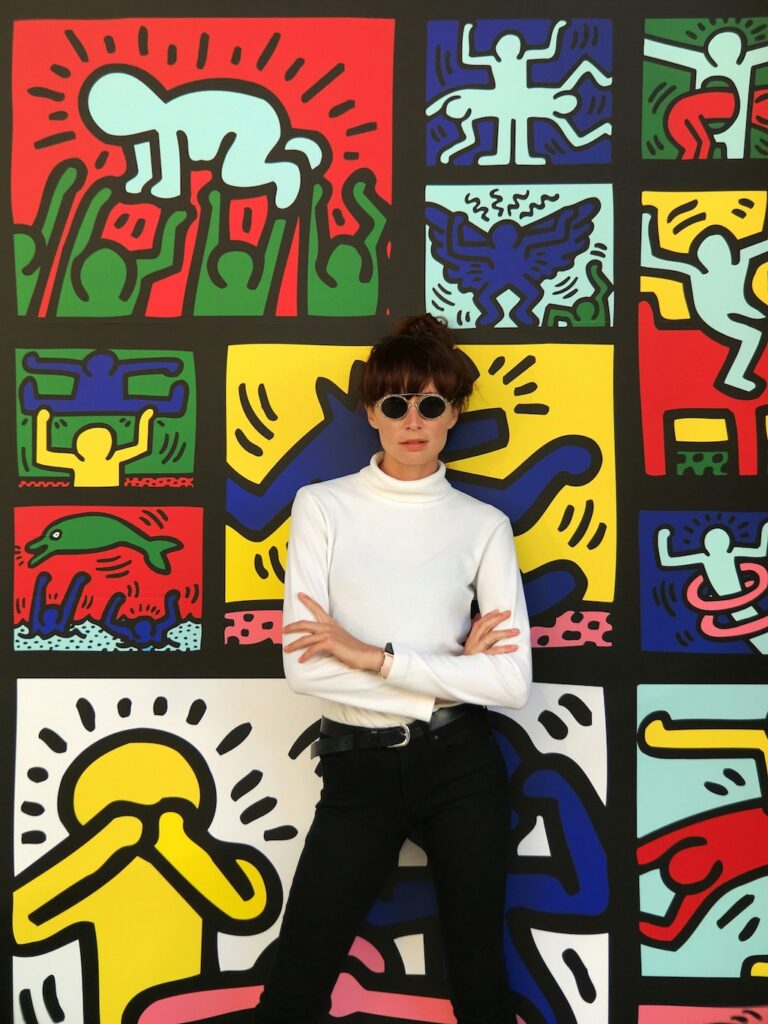 Woman posing for a photo in front of Keith Haring's mural. Photo by Juno Jo. Woman posing for a photo in front of Keith Haring's mural. Photo by Juno Jo.